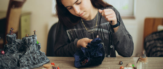 Dice bags for DnD and tabletop RPGs displayed on a gaming table, showing different sizes, materials, and styles for players and Dungeon Masters