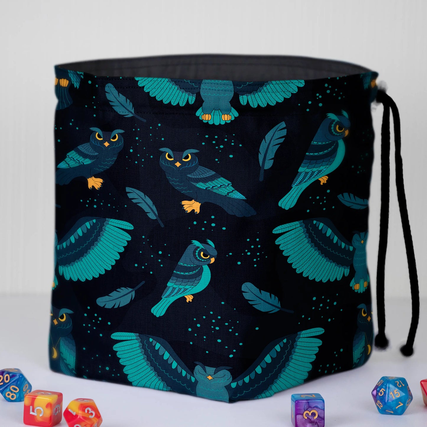 A dice bag that matches your witchy aesthetic — teal night owls and feathers on near-black, holds 300+ dice.