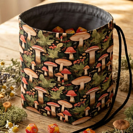 A nature dice bag with leaf and mushroom designs — lush amanita and ferns on forest dark, holds 300+ dice.