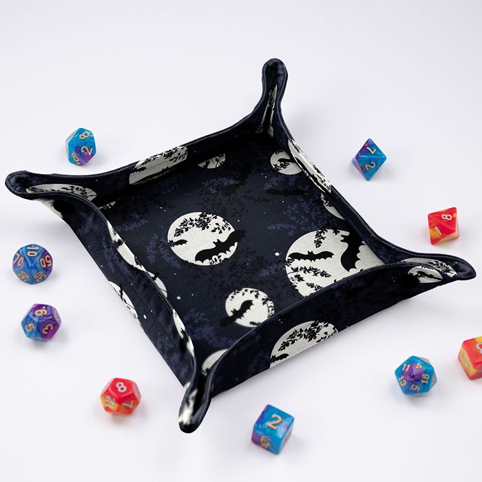 Bat and Full Moon dice tray at an angle, bat silhouettes over glowing full moons on midnight blue, colorful dice around it