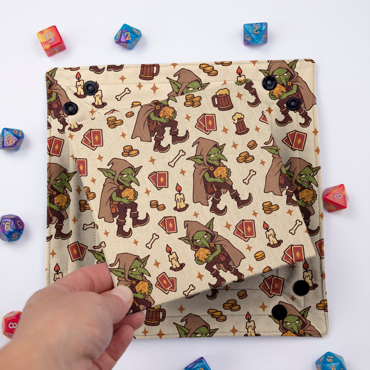 Tavern Goblin dice tray unsnapped and folded flat, hand lifting the removable hard insert covered in the same goblin print