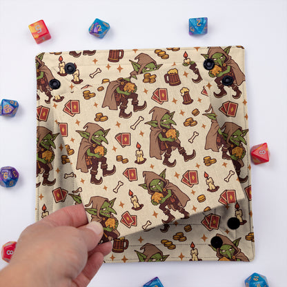 Tavern Goblin dice tray unsnapped and folded flat, hand lifting the removable hard insert covered in the same goblin print