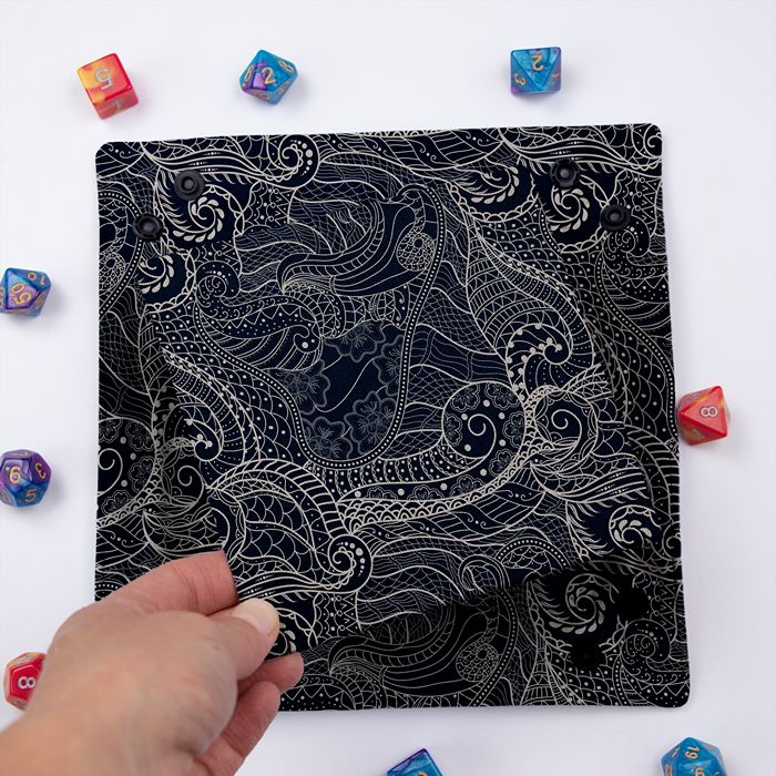 Dragon Scale dice tray folded flat, hand lifting the removable hard insert covered in the same scale print
