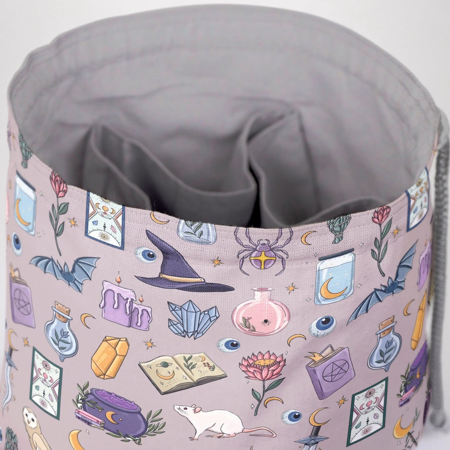 A dice bag that matches your witchy aesthetic — pastel mauve witch print with potions, crystals and bats, holds 300+ dice.