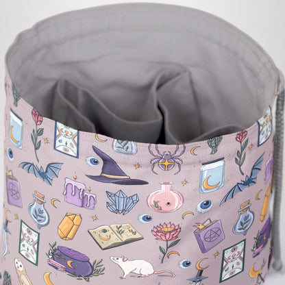 A dice bag that matches your witchy aesthetic — pastel mauve witch print with potions, crystals and bats, holds 300+ dice.
