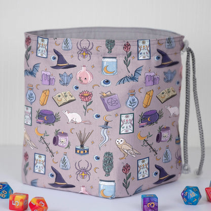 Close-up of the pastel witch print — witch hat, potions, tarot and crystals on dusty mauve gabardine.