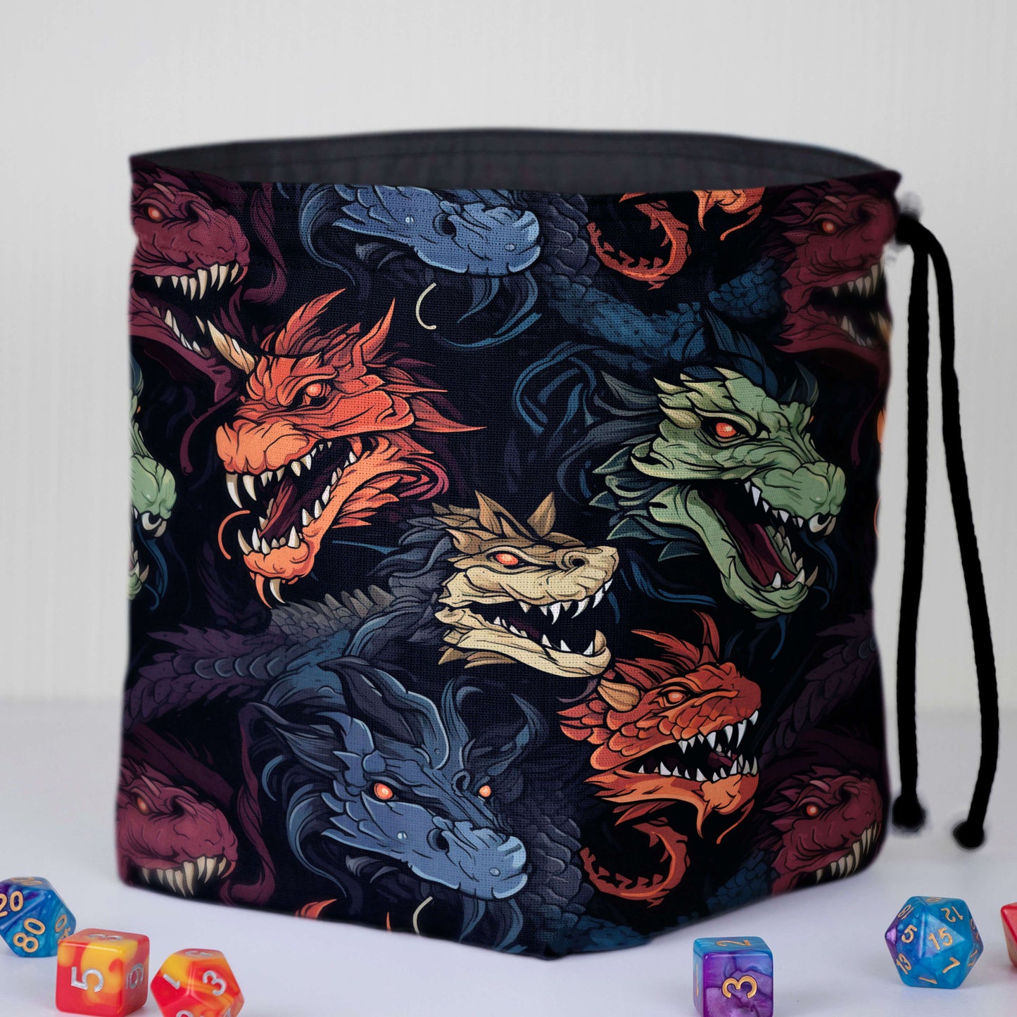 Chromatic dragon dice bag front — detailed multicolor dragon heads on black gabardine.