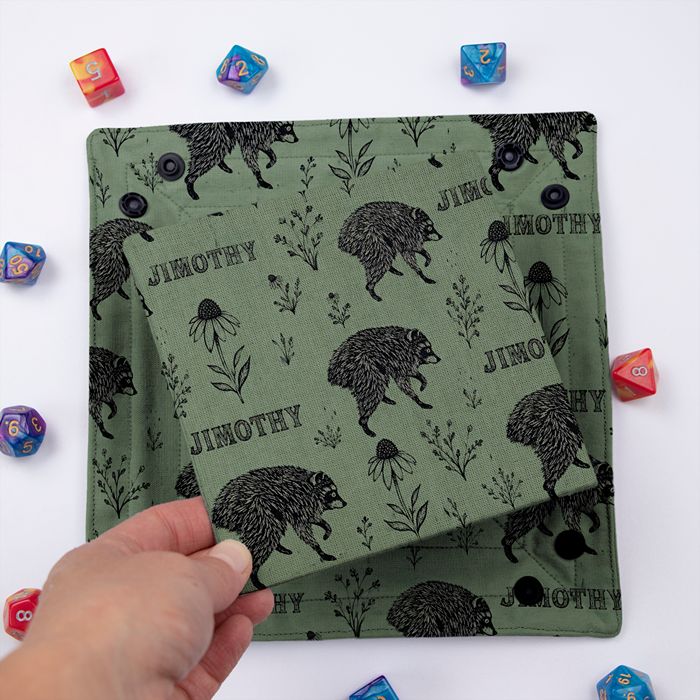Jimothy sage dice tray folded flat, hand lifting the removable hard insert covered in the same print