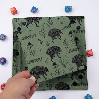 Jimothy sage dice tray folded flat, hand lifting the removable hard insert covered in the same print