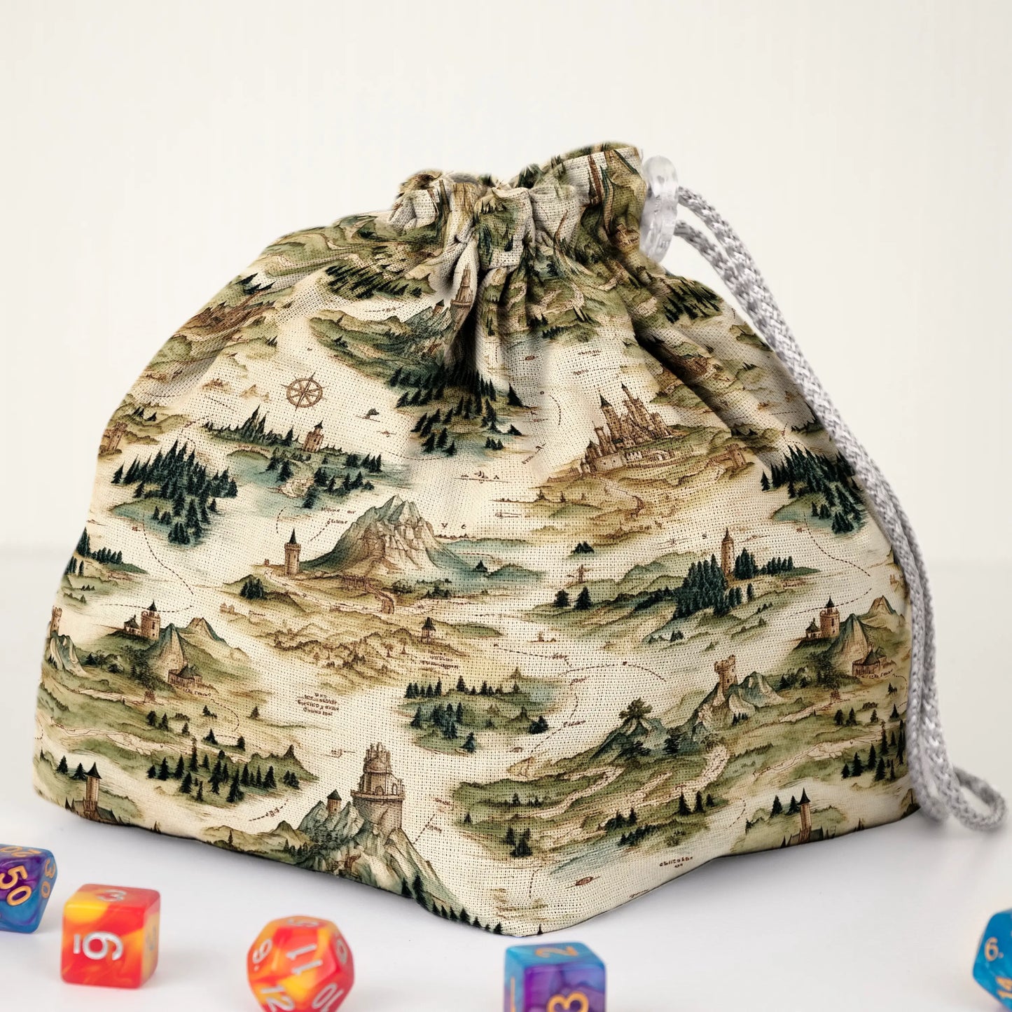 Close-up of the fantasy map print — mountains, forests and compass roses on cream gabardine.
