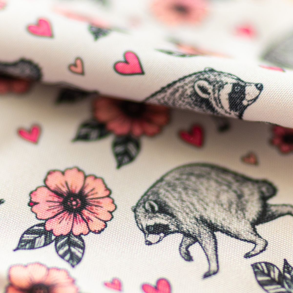 Close-up of GameFancy Jimothy raccoon print fabric, pink blossom design, used for handmade dice bags