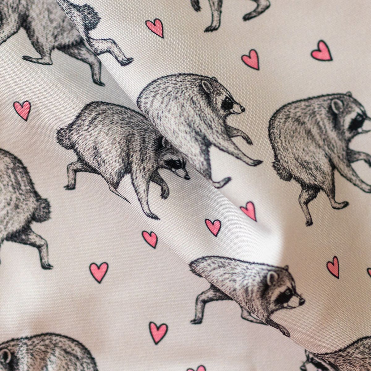 Close-up of GameFancy Jimothy raccoon print fabric, grey hearts design, used for handmade dice bags