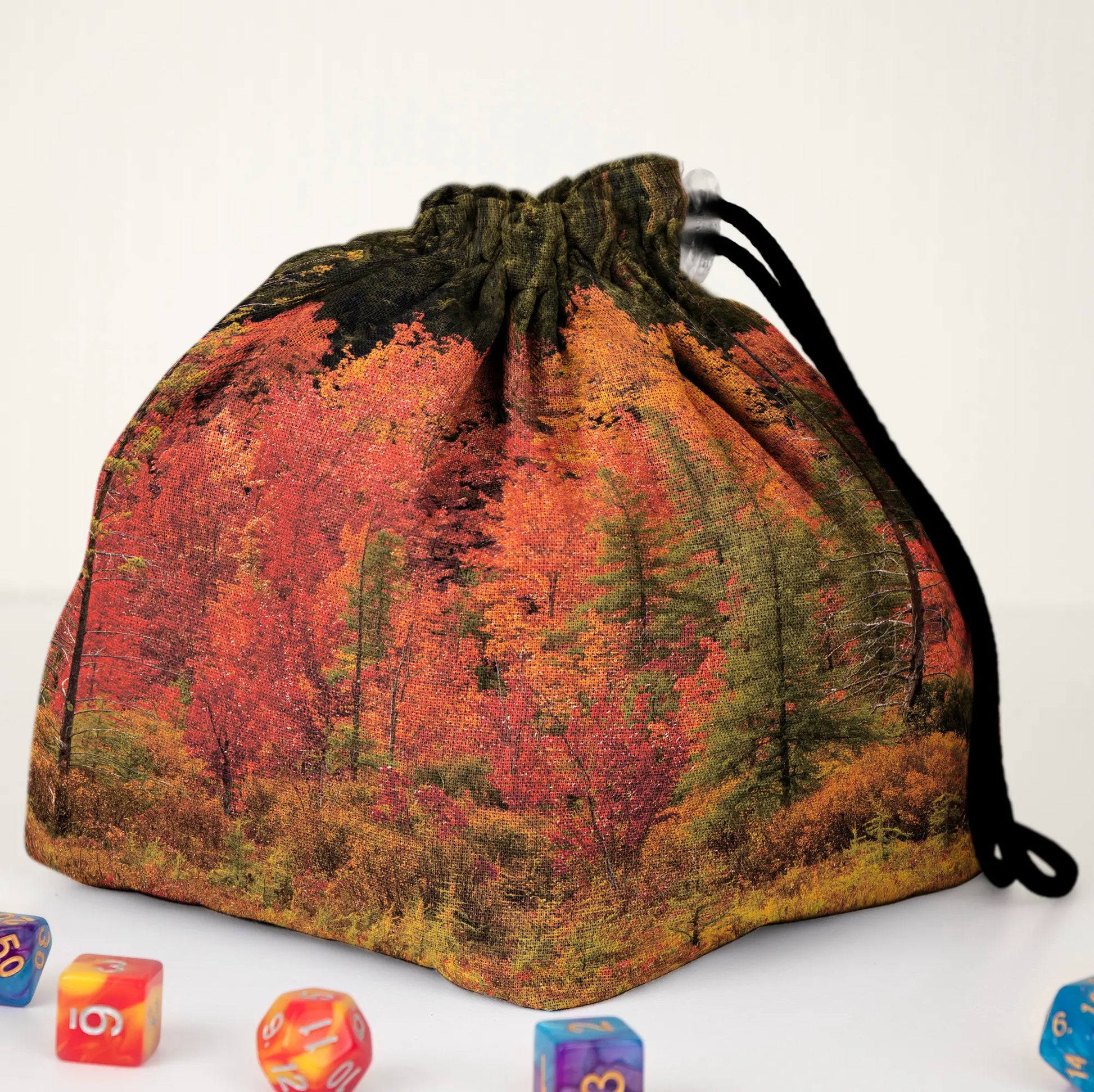 A cottagecore nature dice bag — a cosy autumn forest of red and gold trees, holds 300+ dice.