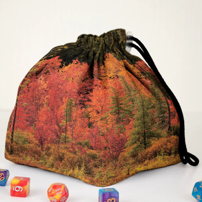 A cottagecore nature dice bag — a cosy autumn forest of red and gold trees, holds 300+ dice.