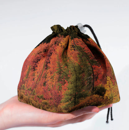 Close-up of the autumn forest print — red, orange and green woodland on gabardine.