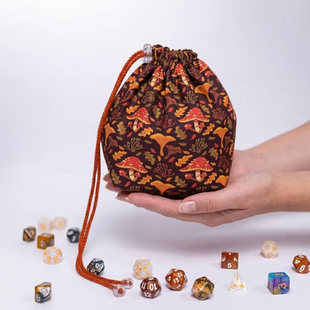 A nature dice bag with mushroom designs — red caps and chanterelles on warm brown, holds 300+ dice.
