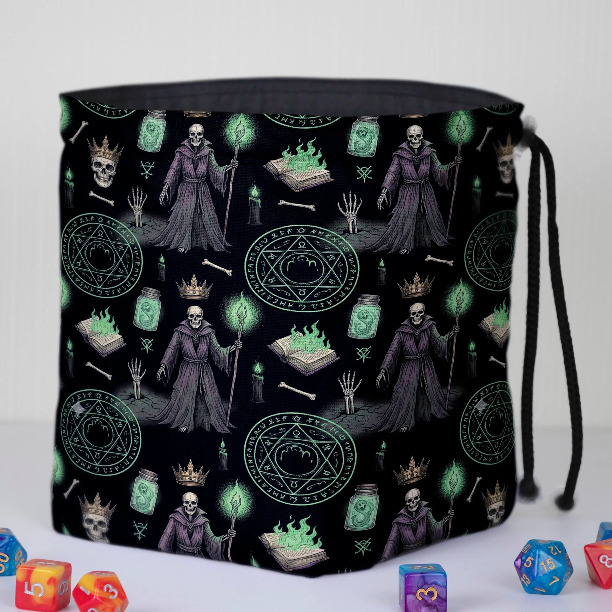 Lich dice bag standing open on the table — robed skeleton liches, spellbooks with green flame and summoning circles, polyhedral dice around