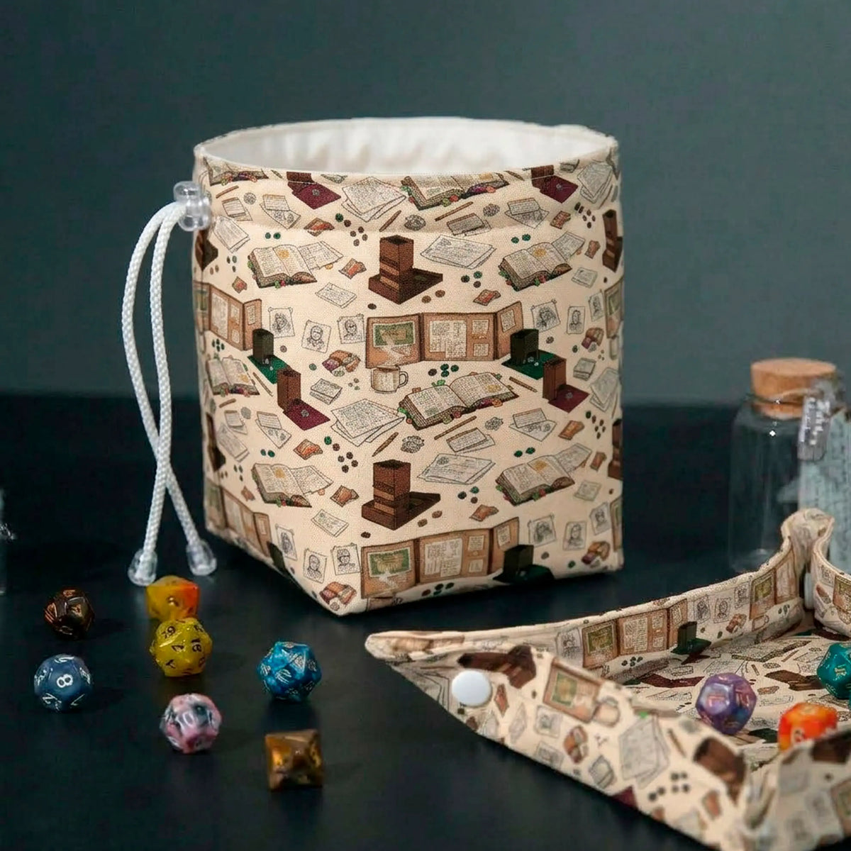 Dungeon Master's Desk dice bag standing open with matching folding dice tray, print of DM screens, dice towers and character sheets