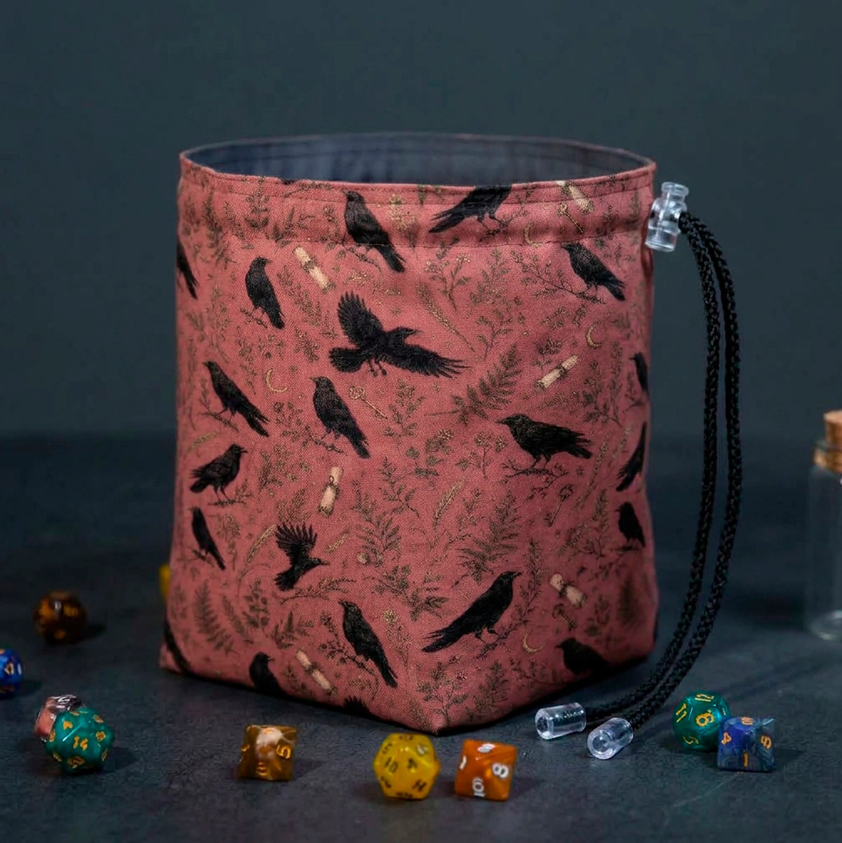 Fernwood Corvus dice bag standing open, terracotta fabric with black crows, ferns and gold crescent moons, dice around the base