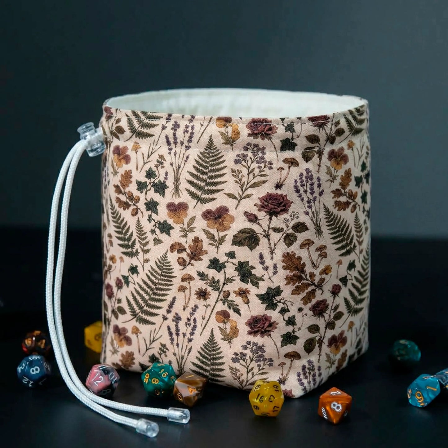 Pressed Hours dice bag standing open on the table, pressed flowers and fern print on cream fabric, white cotton lining visible