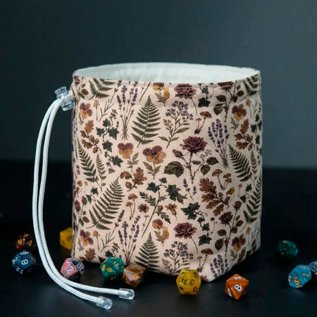 Pressed Hours dice bag standing open on the table, pressed flowers and fern print on cream fabric, white cotton lining visible