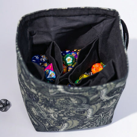 Handmade black-and-white dragon dice bag open to show 6 pockets and colorful dice — 300+ capacity.