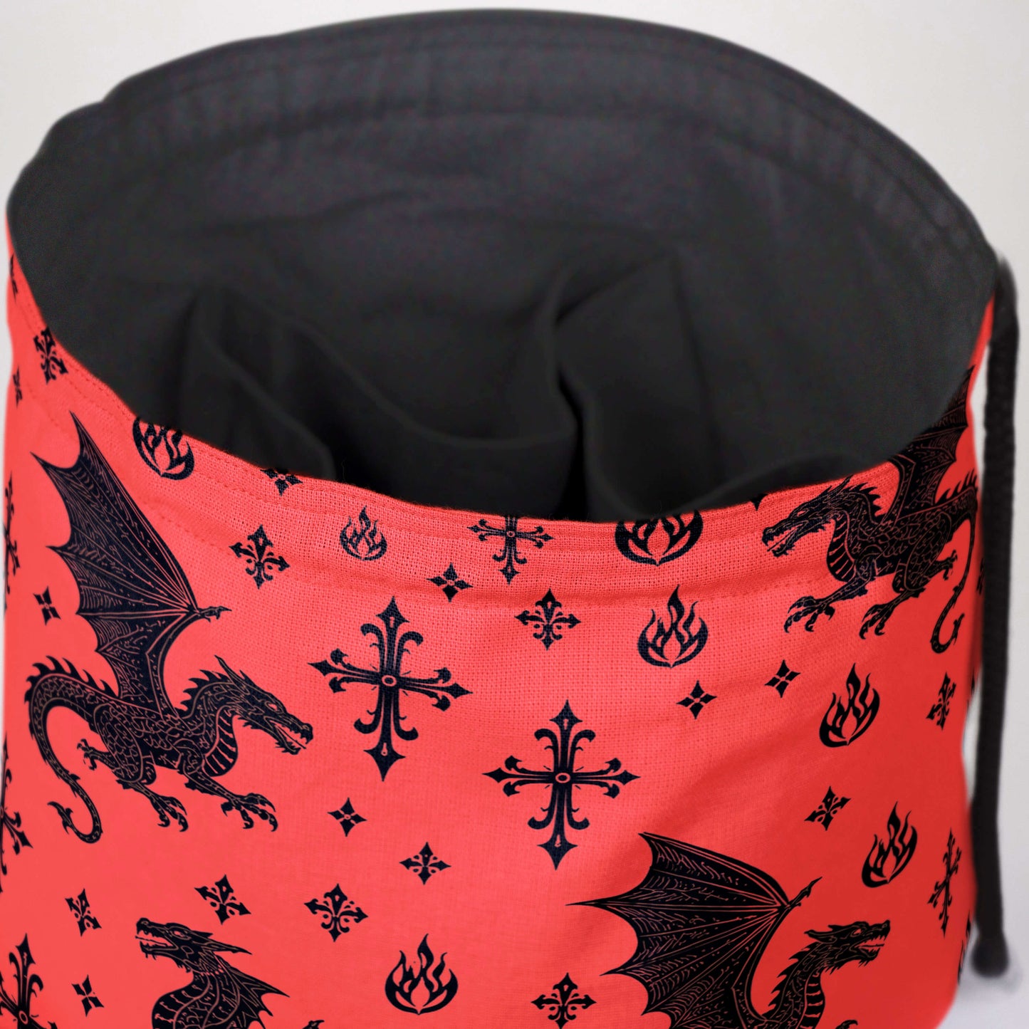 Close-up of the red dragon print — black heraldic dragons and gothic crosses on gabardine.