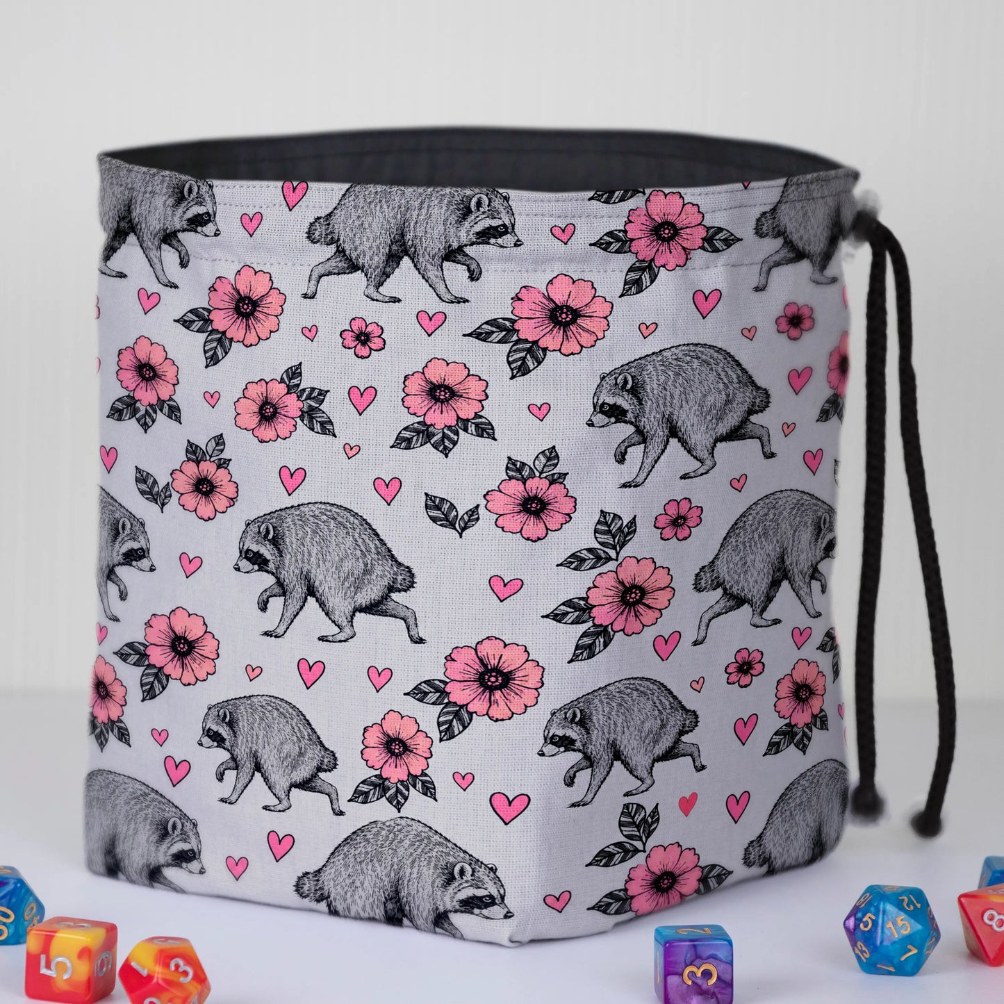 Pink Blossom Jimothy dice bag standing open on its square base with dark lining, raccoons and hearts print