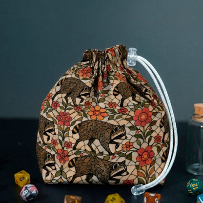 Jimothy raccoon dice bag in warm stained glass garden print with cream, red and orange flowers, with DnD dice