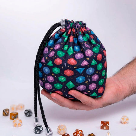 Gemstone dice bag with pockets held in one hand, navy fabric covered in bright red, green, blue and purple gem-cut dice