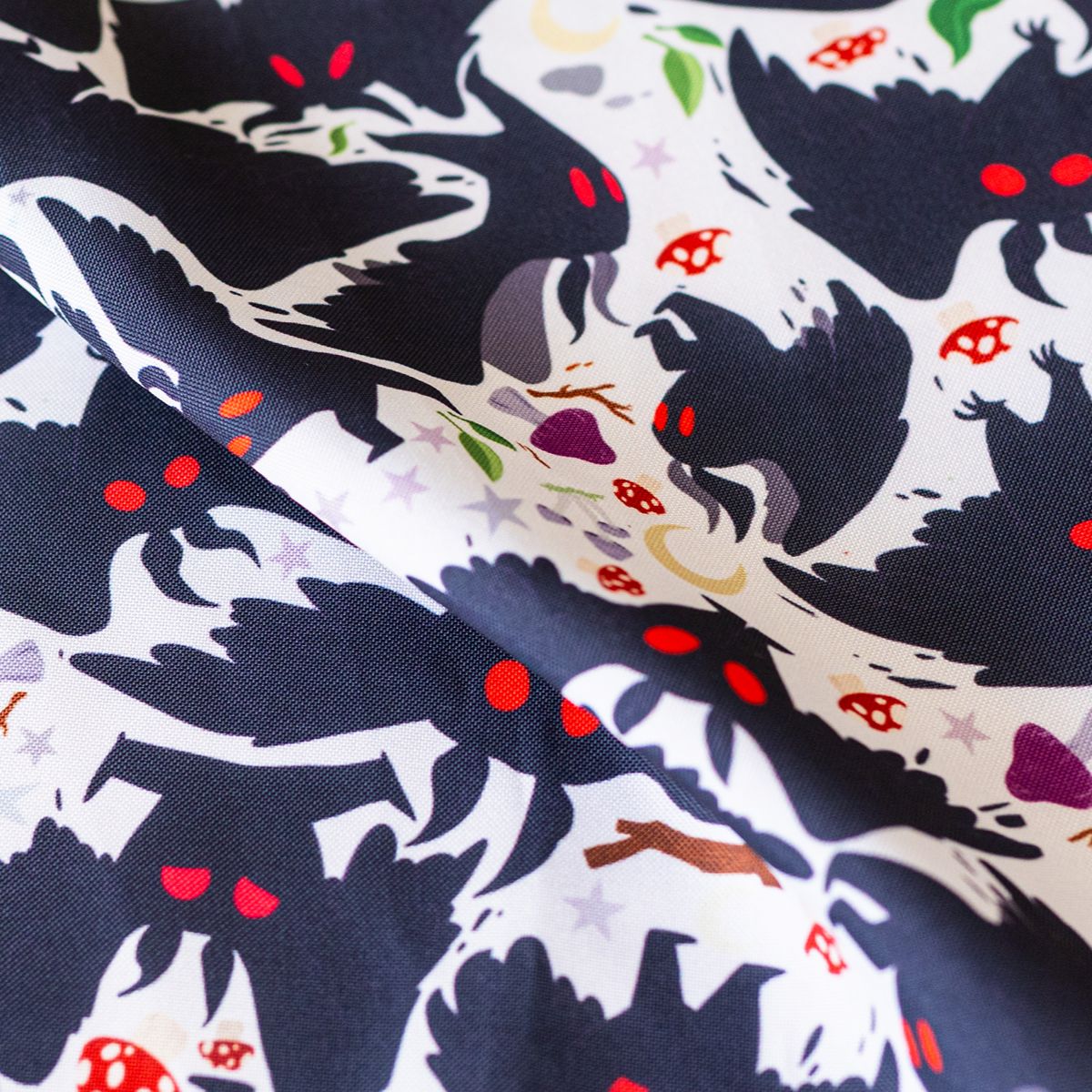 Close-up of GameFancy dark mothman print fabric, cryptid design, used for handmade dice bags and trays