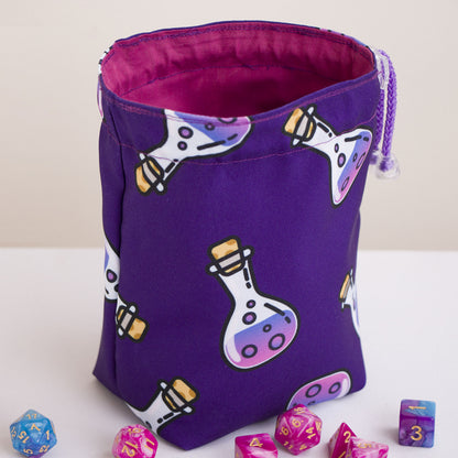 Purple potion print custom dice bag open, pink cotton lining, DnD dice sets beside