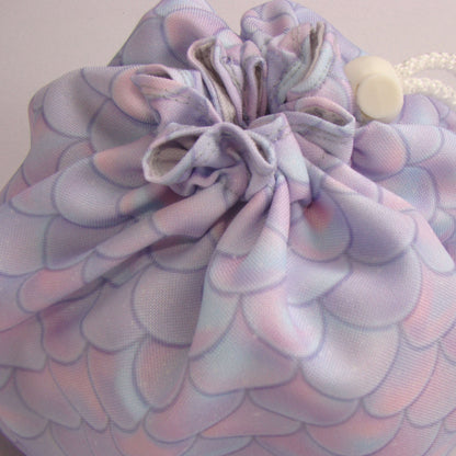 Pastel dragon-scale dice bag with white drawstring drawn closed — handmade fantasy pouch.