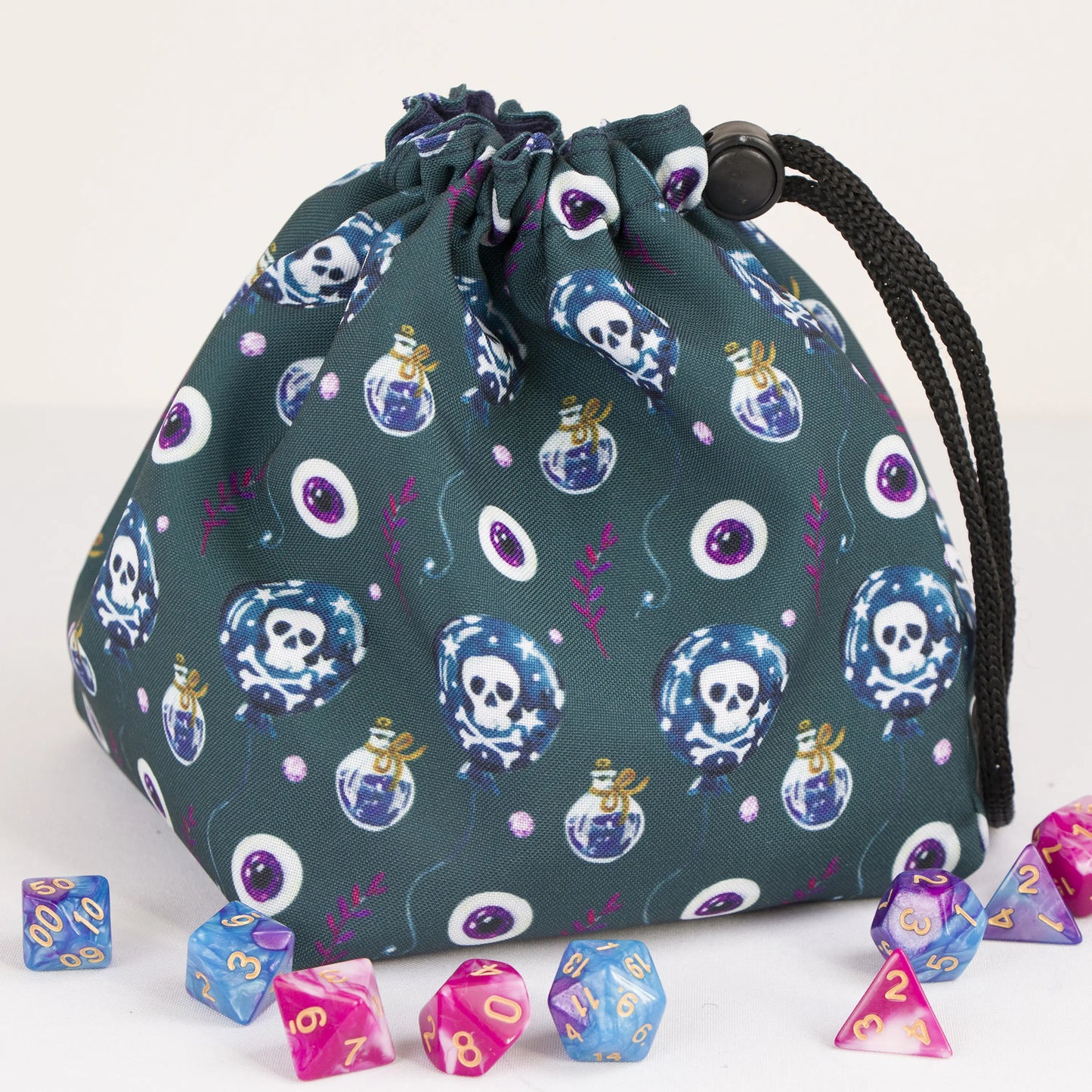 A dice bag that matches your witchy aesthetic — poison bottles, skulls and eyes on dark teal, holds 300+ dice.