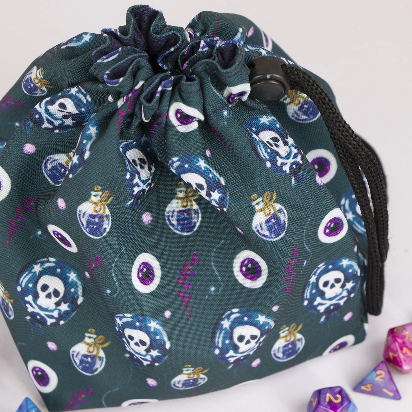 Close-up of the poison and skull print — potion bottles, skulls and eyeballs on teal gabardine.