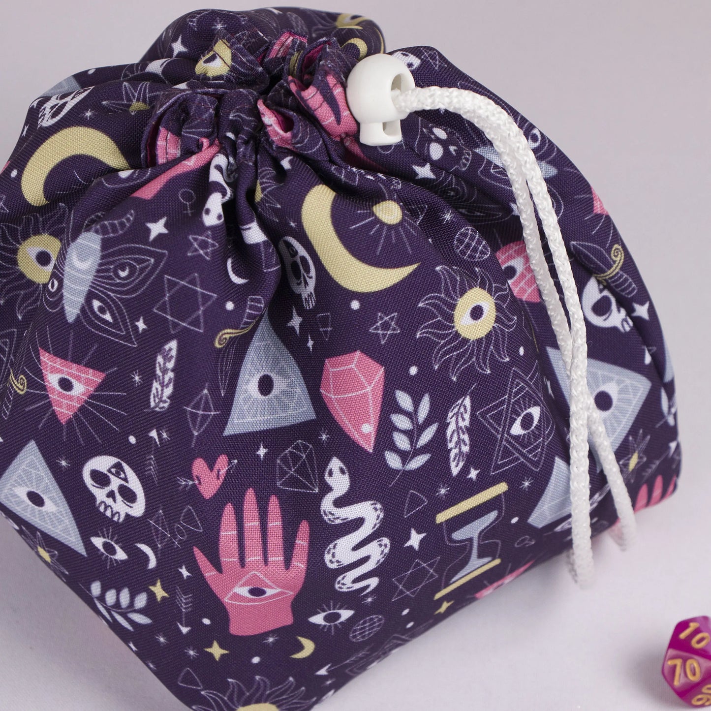 Close-up of the mystic hand print — palmistry hand, eyes in triangles, skulls and snakes on purple gabardine.