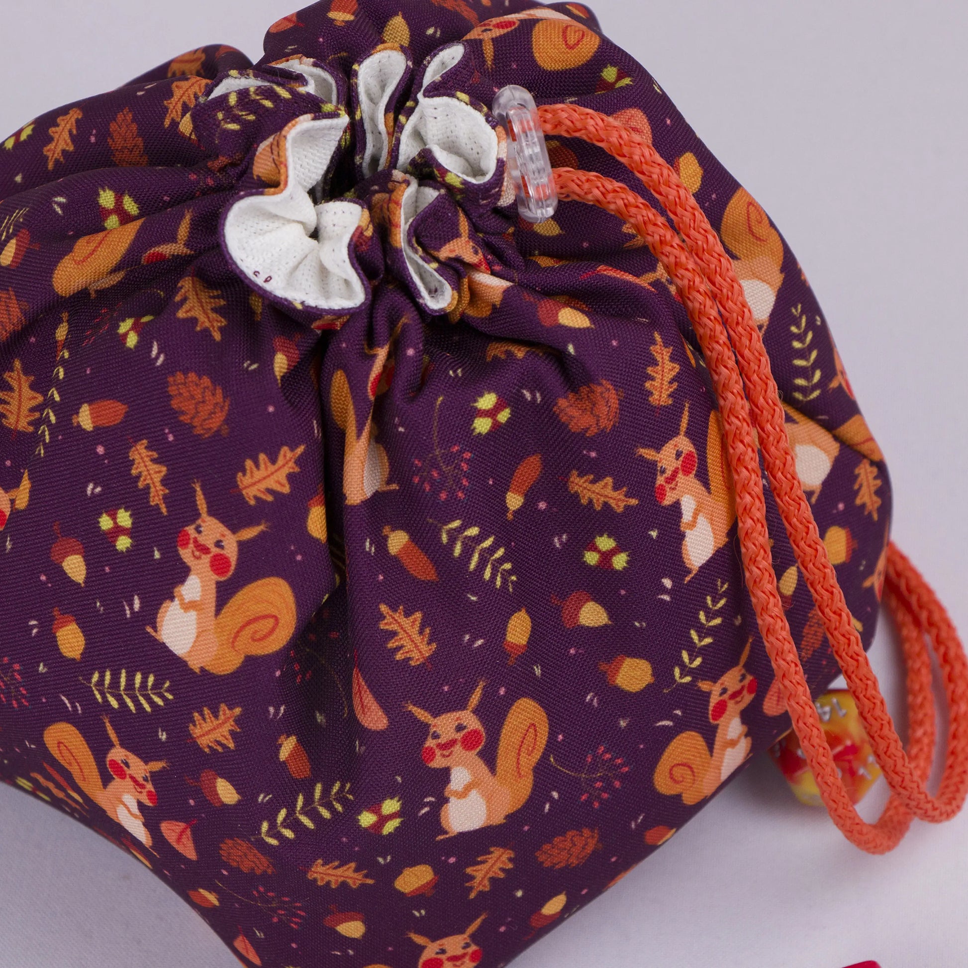 Close-up of the squirrel print — orange squirrels, acorns and oak leaves on plum gabardine.