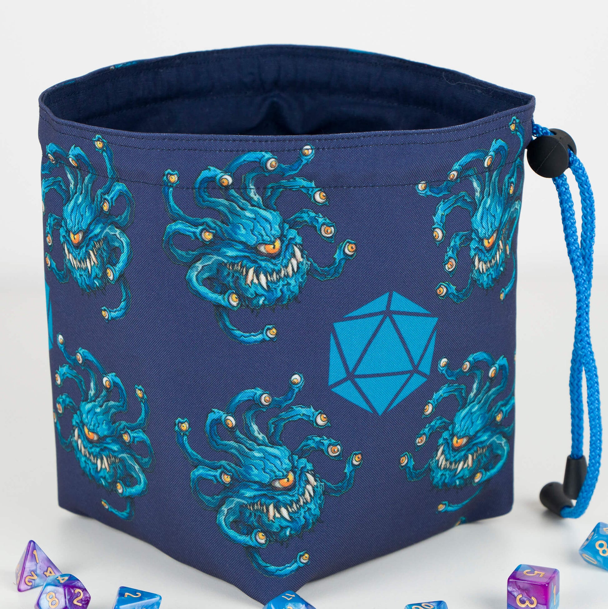 Close-up of the beholder artwork — teal eye tyrant with eyestalks on navy gabardine.