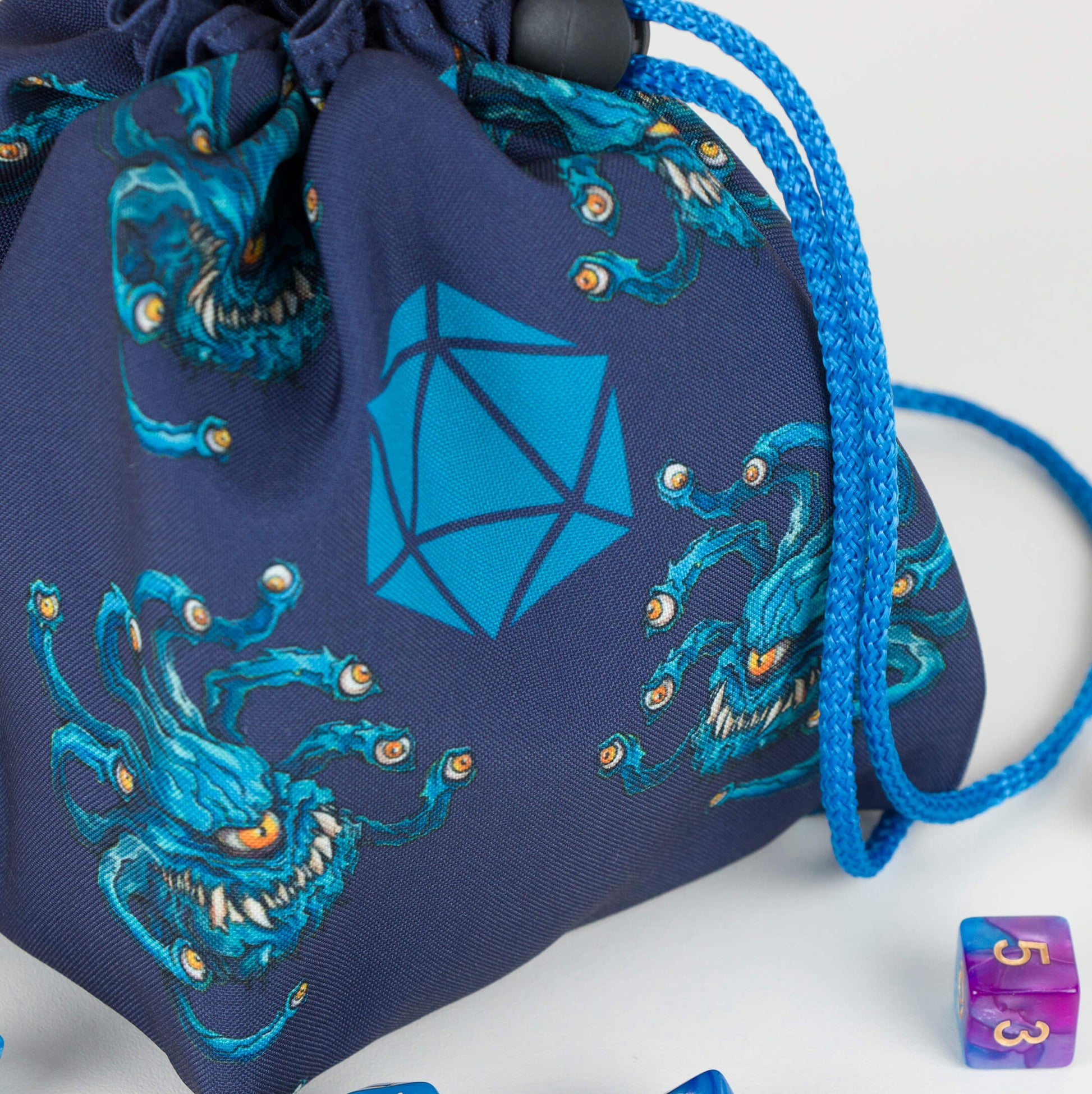 Beholder dice bag front view — teal beholders with eyestalks on navy fabric, blue drawstring.