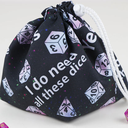 Close-up of the print reading 'Yes I do need all these dice' with pastel polyhedral dice on black gabardine.