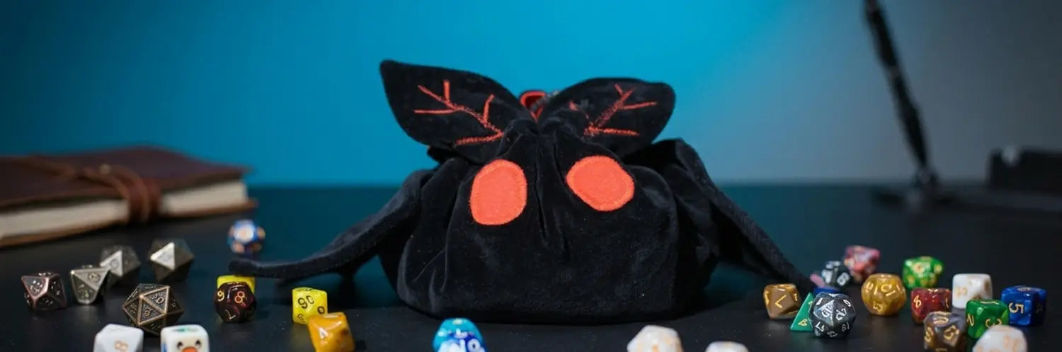 Handmade plush Mothman dice bag with embroidered red eyes — cryptid DnD accessory for Mothman fans.