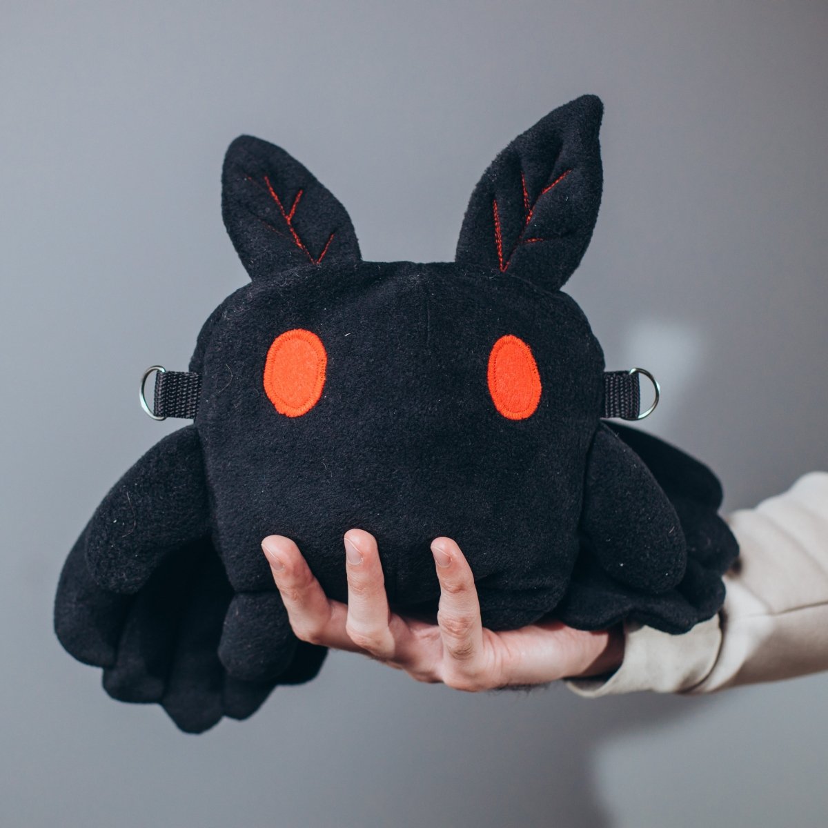 Handmade mothman plush dice bag held in hands — soft cryptid DnD accessory by GameFancy