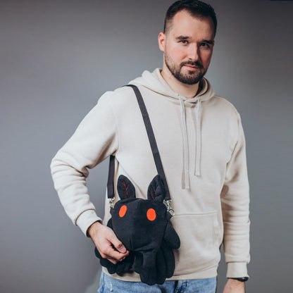 Man wearing mothman plush dice bag with long strap — GameFancy cryptid gift
